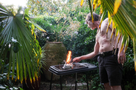 Man Grilling in Garden With Plants and Fire 