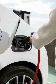 Person charging an electric car at charging station