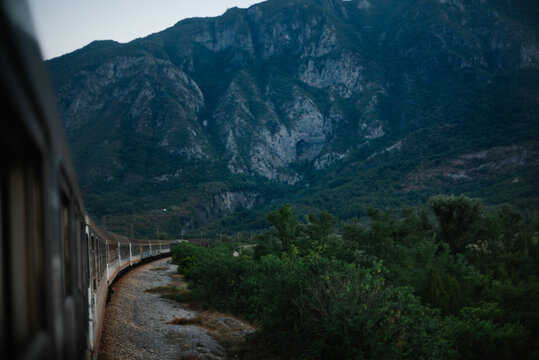 Passenger train curving beneath rocky mountain landscape