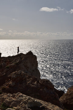 Playful silhouette on rocky ridge above shimmering sea