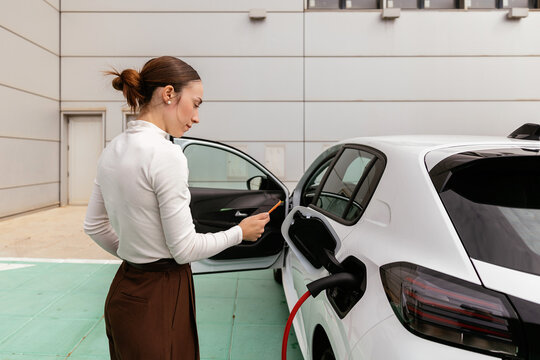 Woman charging electric car, sustainable urban transportation concept