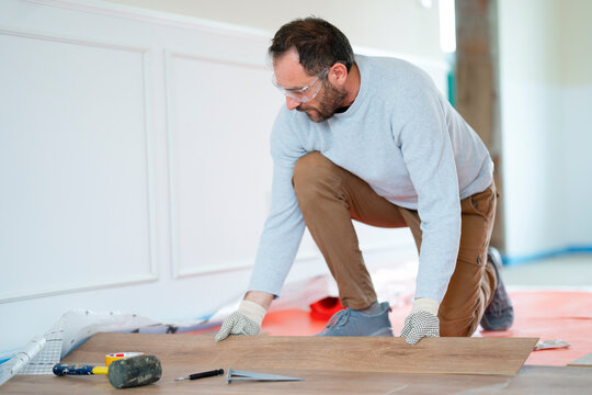 Man installs floor tiles in a building renovation