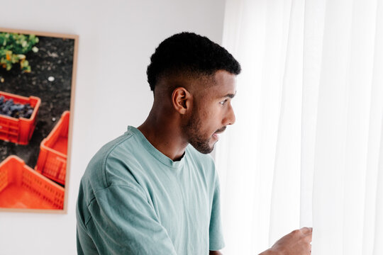 Black man leaning out of his window with a pensive expression