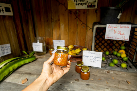 POV ugc Hand holding jar of chutney at roadside fruit stall.