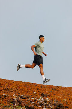 A full-body perspective shows a trail runner accelerating downhill