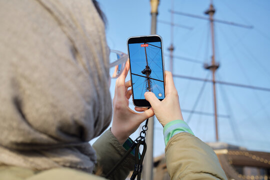 Person taking a picture of a ship's mast with a smartphone