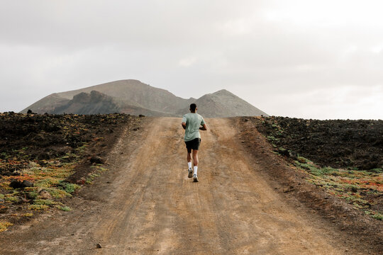 Trail runner seen from behind, running along a dirt road