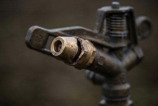 Full frame texture of agricultural sprinkler brass nozzle split open by frost damage