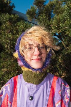 Smiling woman in colorful knit hood and glasses outdoors