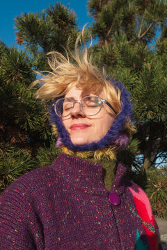 Woman with windblown hair in knitted hood enjoying sunlight
