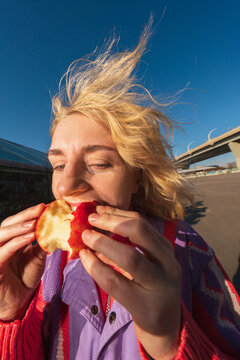Woman eating red apple with windblown hair outdoors