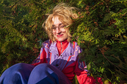 Woman in colorful sweater relaxing among green foliage