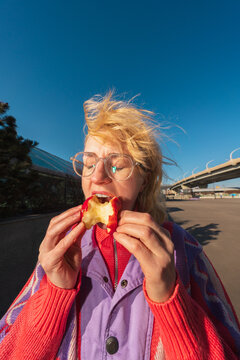 Woman eating apple in sunlight with windblown hair outdoors
