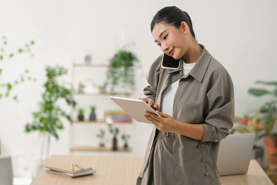 Young Asian woman multitasking with phone and tablet