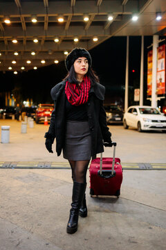 Woman pulling suitcase at night