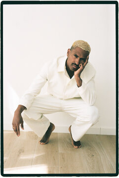 Man crouching on floor with hand on face