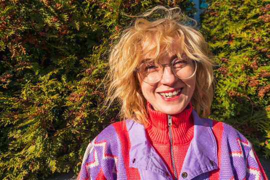Happy woman with windblown hair in colorful sweater outdoors