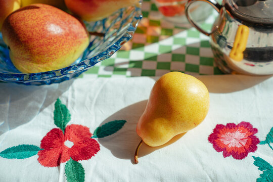 Fresh pears on a table with a colorful cloth and dish