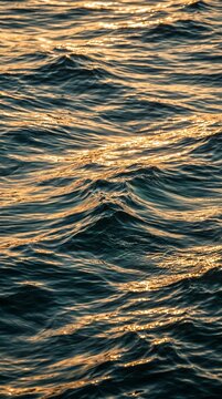 high angle close up of the ripples of water of a sea at summer sunset. sunlight shines on the soft surface of ocean at hot weather.