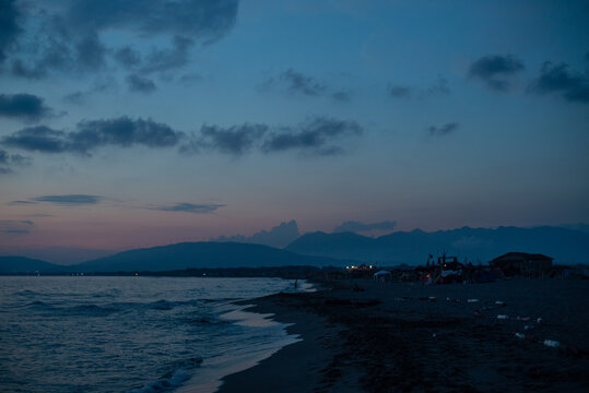 Beach shoreline at dusk with tents and mountains in distance