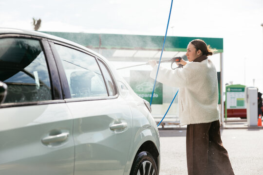 Woman washing electric car at self-service car wash