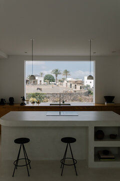 Within a contemporary interior, a kitchen is outlined by a wide window