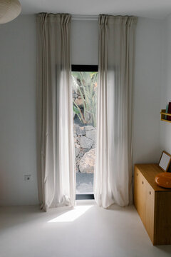 A window with long curtains, inside a room in a modern home