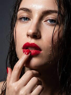 Wet beauty close up portrait with glossy red lips red manicure and radiant skin