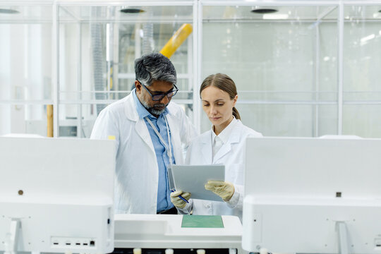 Young female scientist in white coat standing in laboratory