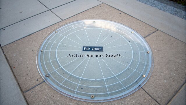 Circular Stone Diagram at Fair Center Featuring the Inspiring Message Justice Anchors Growth Set on Urban Pavement in Modern City Environment