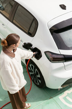 Woman charging electric car at sustainable station