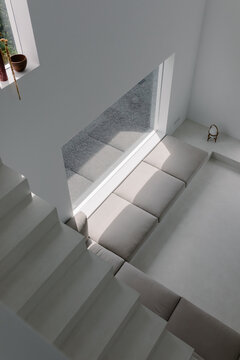 Minimalist armchair bathed in light viewed from the top of a staircase
