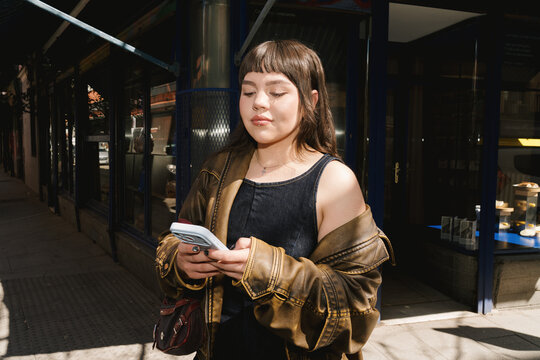Young person enjoying spring outdoors while texting in city street