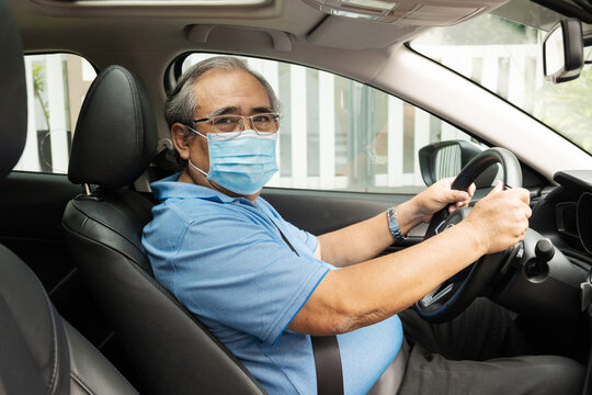 senior man inside his car wearing surgical mask and looking back