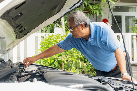 An older man on the road having problem with a car. Broken down car