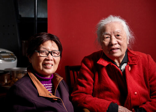Chinese elderly woman and her daughter at home with a red background