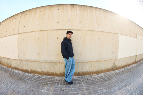 Man stands beside wall in urban area during daylight hours