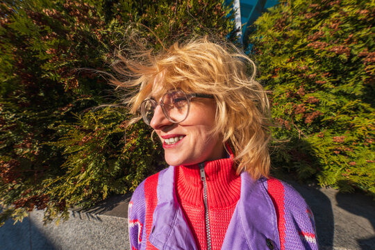 Smiling woman with windblown hair in colorful sweater outdoors