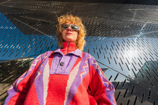 Low angle portrait of woman in colorful sweater and sunglasses