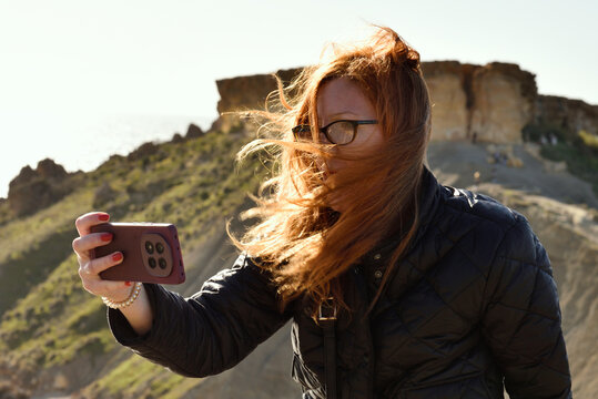 Woman with glasses taking photo in windy sunlight