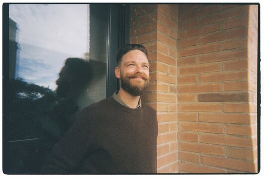 Man Smiles Outside a Brick Building