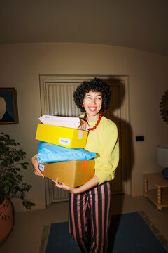Woman smiling holding multiple delivery packages at home