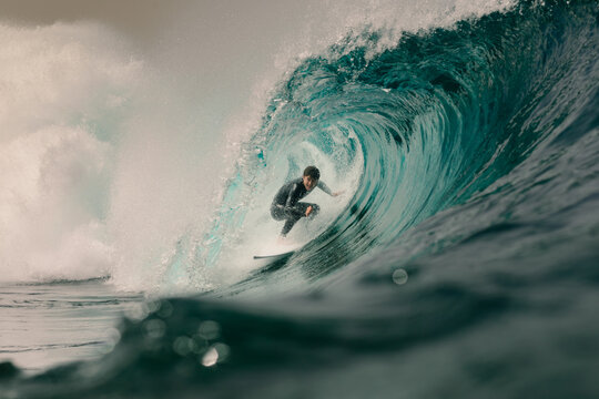 Professional surfer riding the barrel of a massive wave