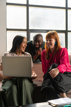 Diverse Coworkers Laughing Over a Laptop During Online Meeting