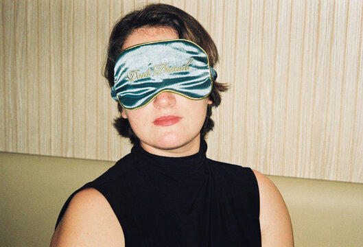 Woman Sits With Sleep Mask in a Stylish Indoor Setting