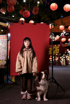 Chinese girl and a dog beneath a lantern-hung tree in a garden