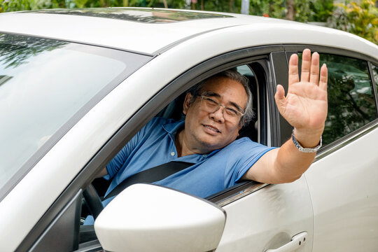 happy an older man open window of a car and raising his hand