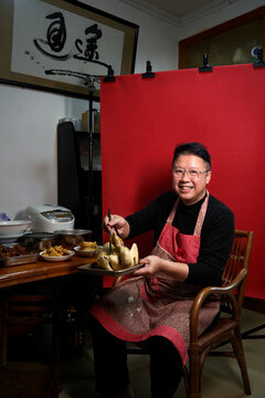 A middle-aged Chinese man at home with a red background