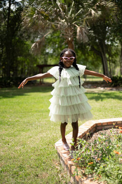 Girl Wearing a Light Dress and Sunglasses Stands on Garden Edge