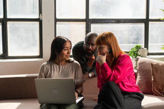 Coworkers Collaborating Over Laptop During Casual Office Meeting